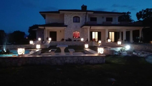 A large, two-story house with a stone facade, a central entrance with a red accent, and a pool area with lights. - Agriturismo Antica Casa Scardone (Piedimonte San Germano)