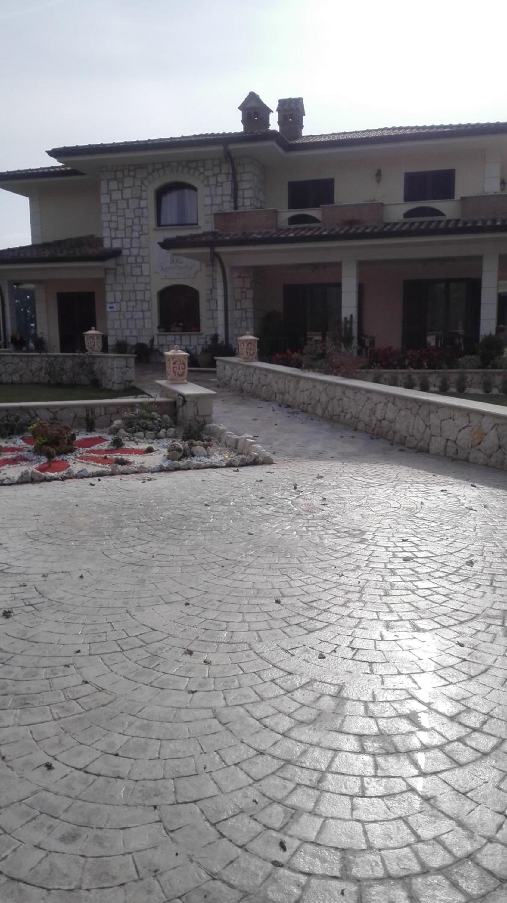 Un amplio patio con un sendero de piedra que conduce a un edificio de fachada de piedra y múltiples ventanas.