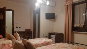 A bedroom with two beds, a desk, a chair, a TV, and an air conditioning unit. - Agriturismo Antica Casa Scardone (Piedimonte San Germano)