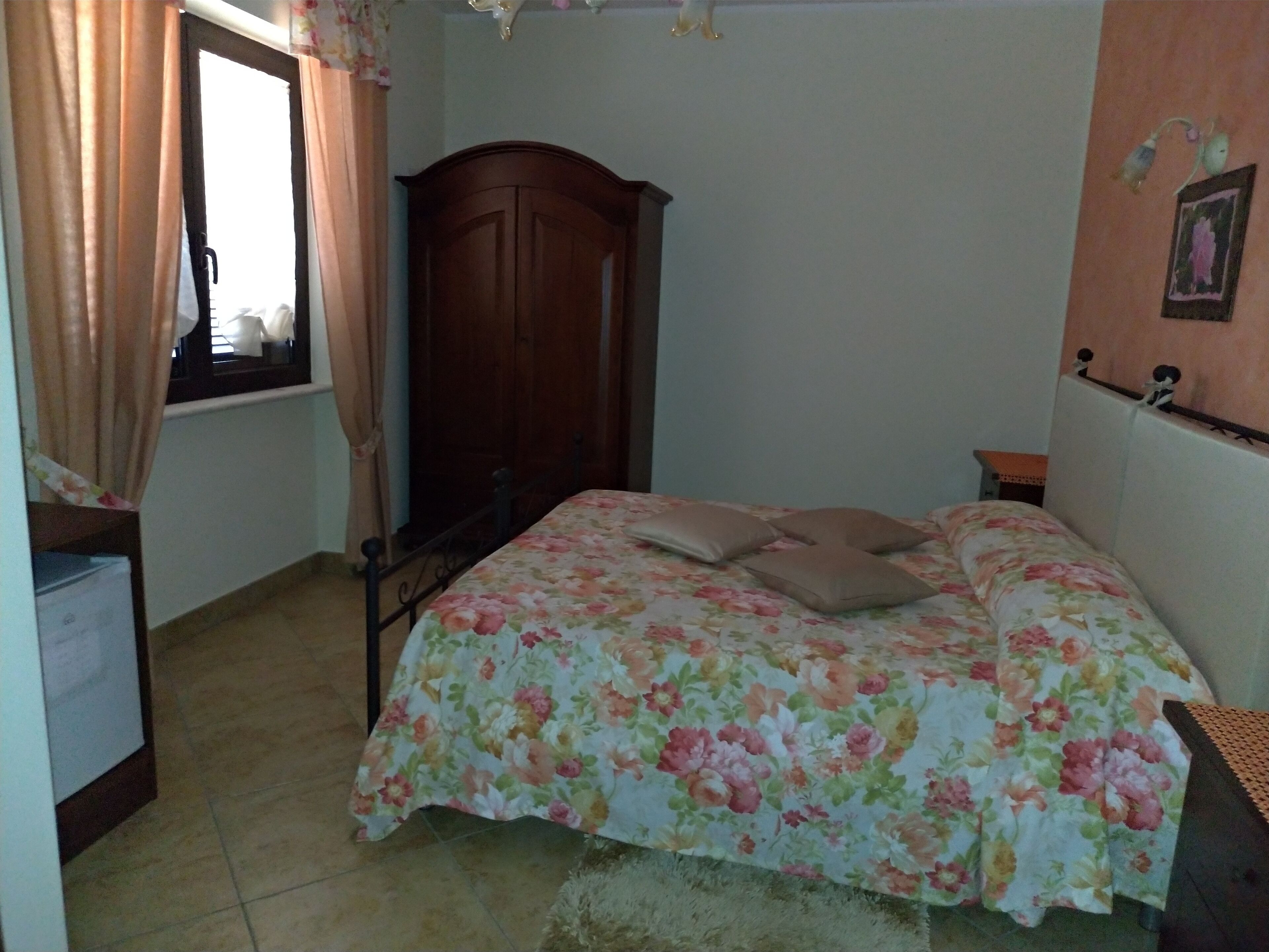 A bedroom with a bed, a wardrobe, a desk, and a window with curtains.
