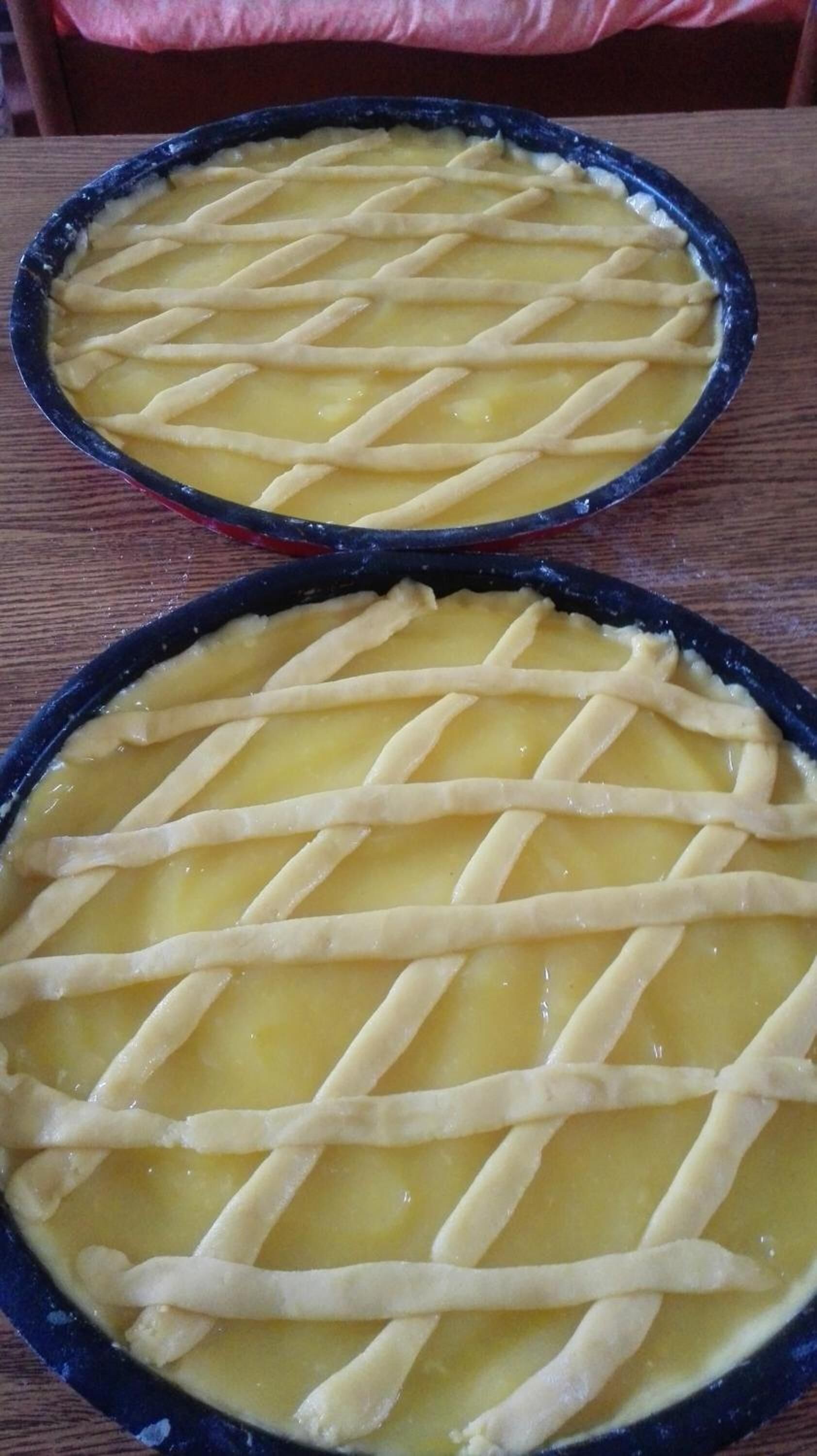 Two round baking dishes with lattice crusts on a wooden surface.