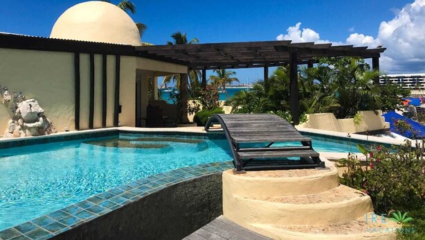 A swimming pool with a sun lounger, a pergola, and a view of the ocean.