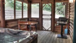 A wooden cabin with a hot tub, a dining table with chairs, and a grill outside. - Southern Charm #88 -Charming & Clean Log Cabin! (Sevierville)