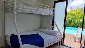 A bunk bed room with a ceiling fan, a view of a swimming pool, and a door leading outside. - Villa Ti Colibri in Sainte-Anne 350 m from the sea (Sainte-Anne)