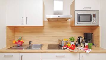 Cocina moderna con armarios blancos, un lavamanos de acero inoxidable, un microondas y una cafetera.