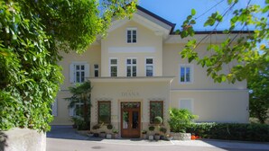 A two-story building with a beige facade, a central entrance with a wooden door, and multiple windows. - Residence Diana (Merano)