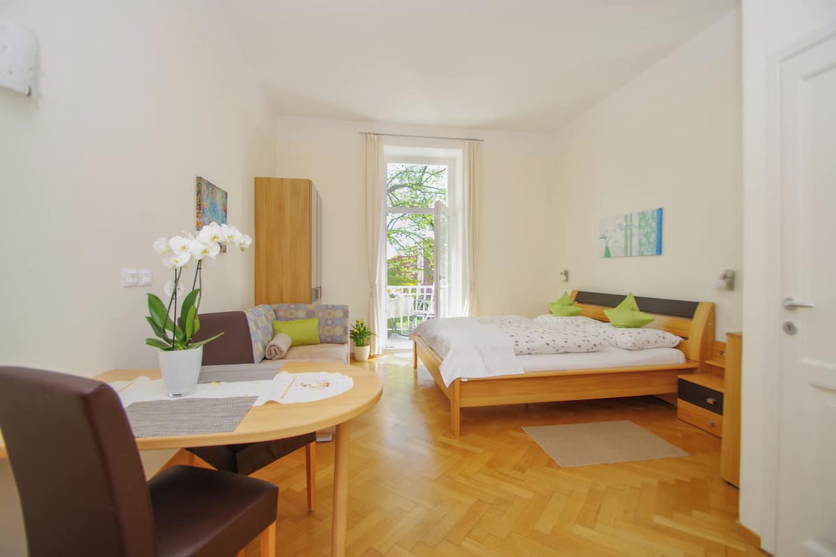 Une chambre à coucher avec un lit, une armoire en bois, une table à manger avec des chaises et une plante en pot.