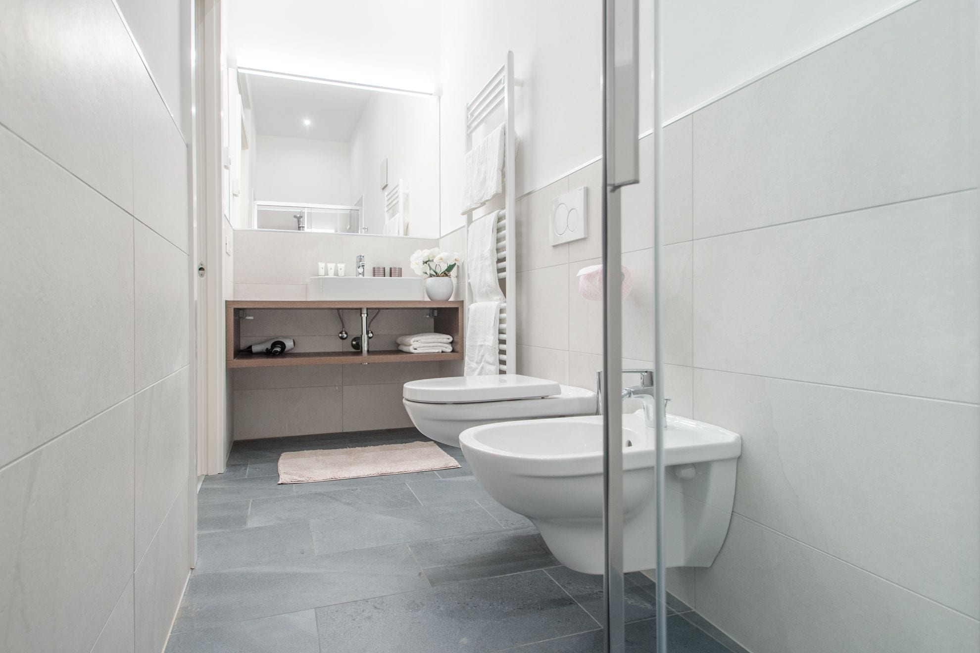 A modern bathroom with a glass shower enclosure, a white sink, and a toilet.