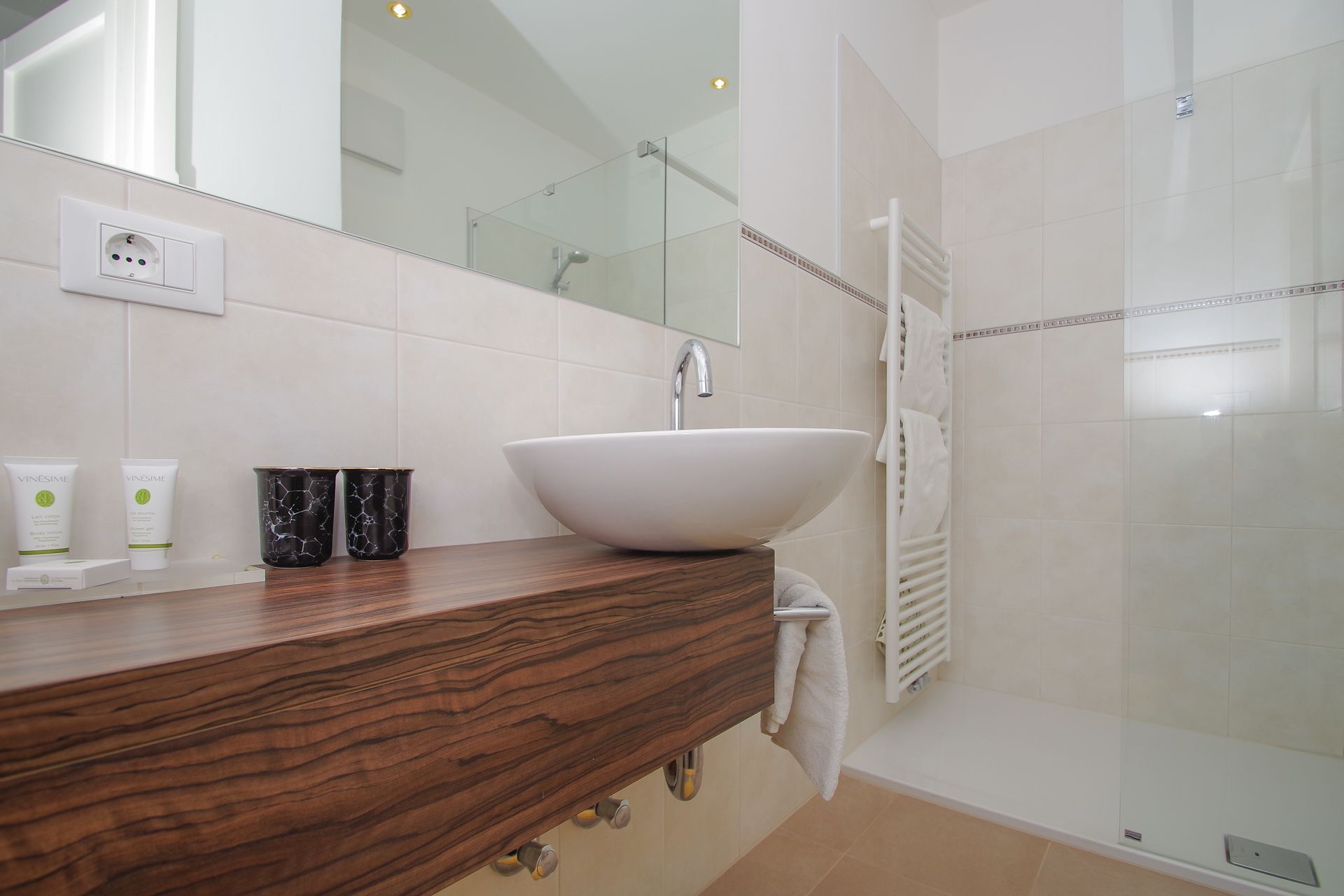 A bathroom with a wooden vanity, a white sink, and a glass shower enclosure.