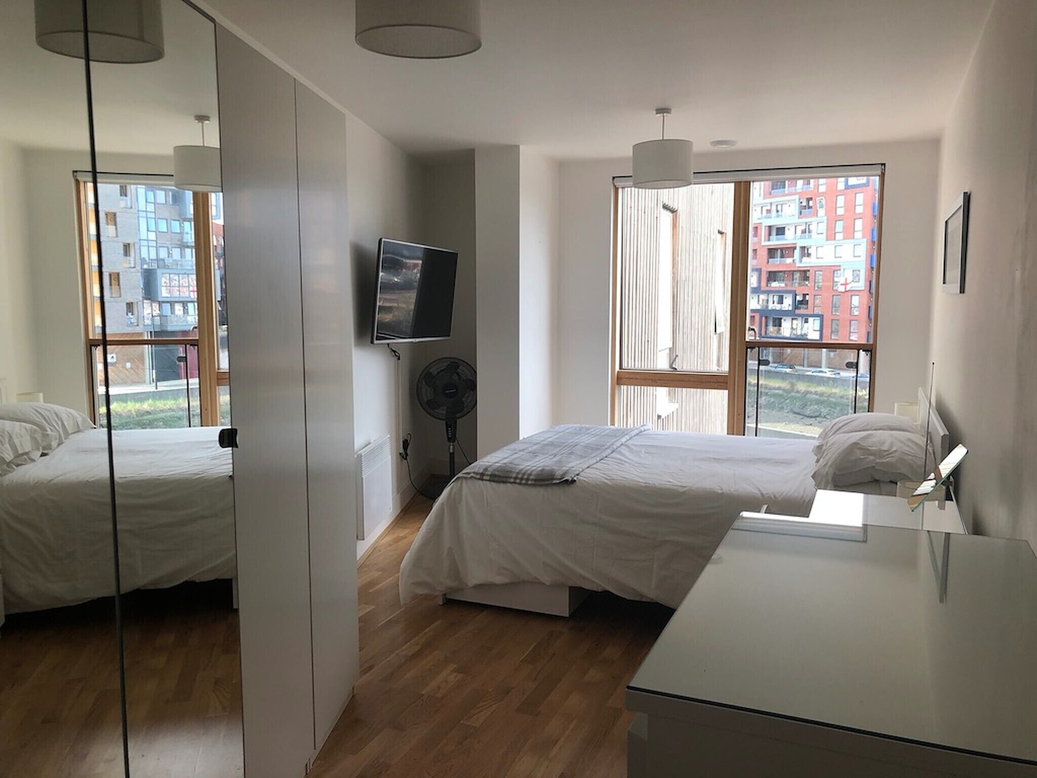 Un dormitorio moderno con dos camas, un televisor y un ventanal con vistas a la ciudad.