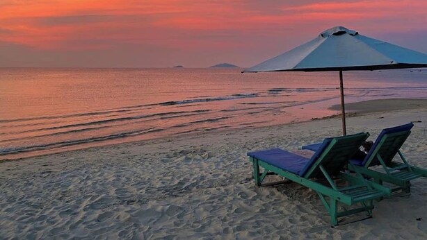 Uma praia com duas cadeiras de praia e um guarda-sol.