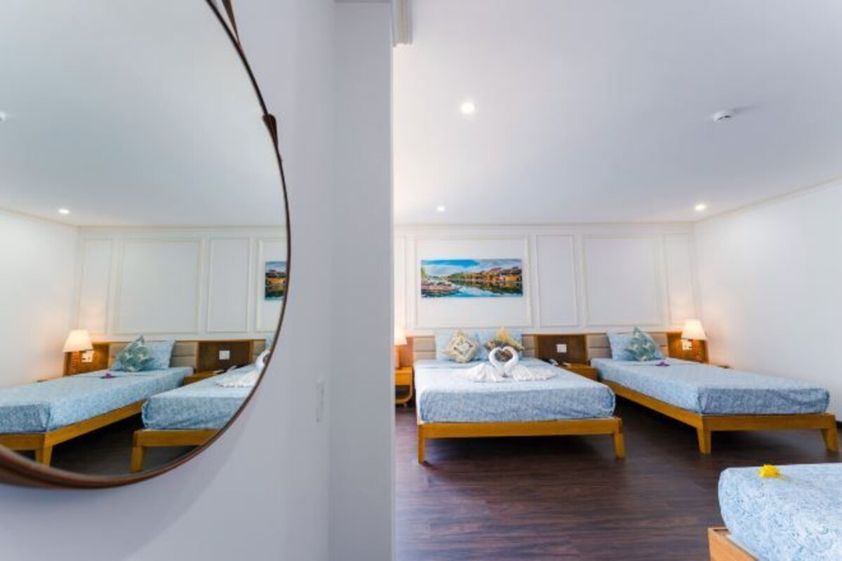 A hotel room with two single beds, a large mirror, and a painting on the wall.