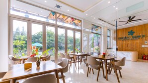 Restaurante moderno com janelas amplas, mesas e cadeiras de madeira.