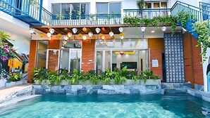 Um hotel com piscina, fachada de madeira e guarda-corpos azuis.
