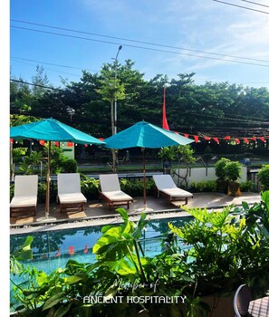 Een buitenzwembad, ligstoelen bij het zwembad