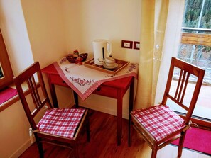 Quarto nos cantos com uma mesa de madeira e duas cadeiras, cada uma com toalha de mesa xadrez.