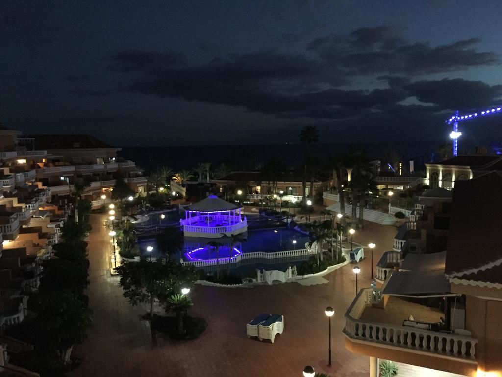 Un resort con zona de piscina central, varias edificaciones y vista al mar.