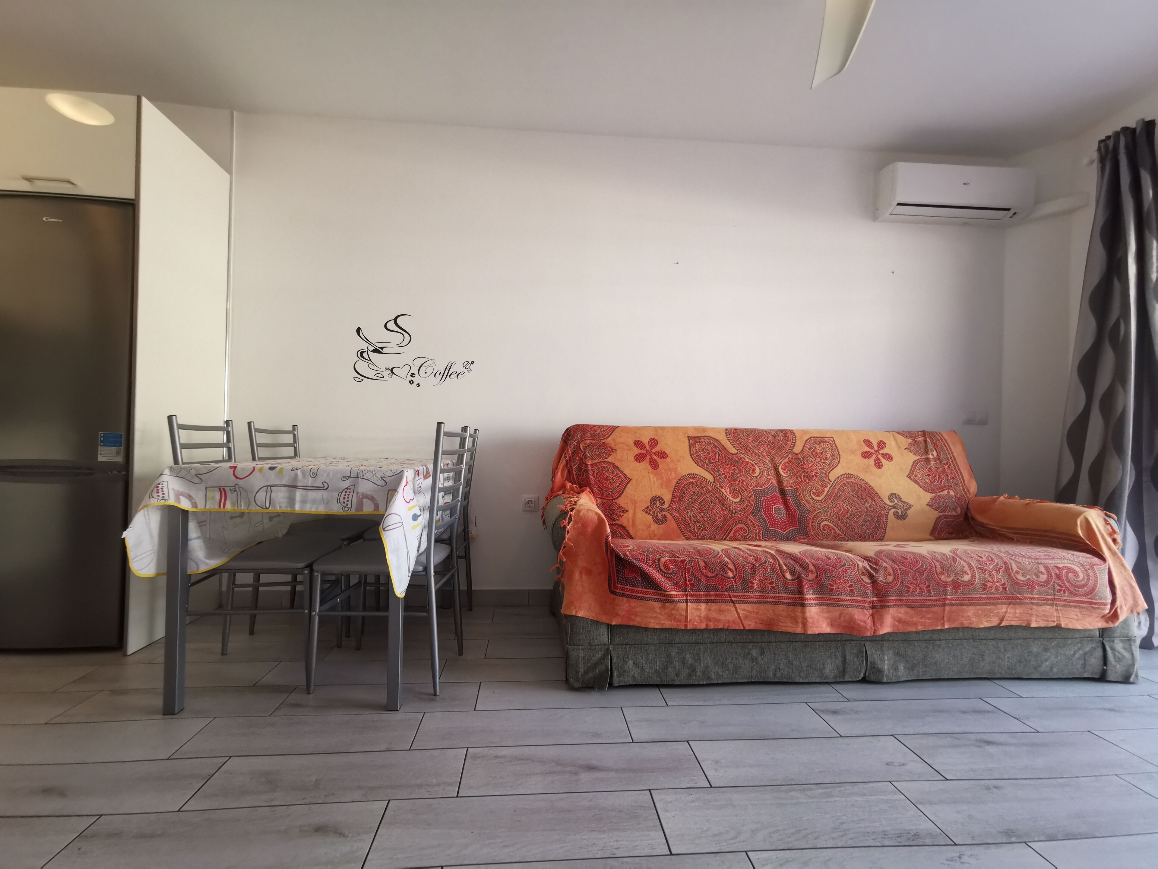 Ein Wohnzimmer mit einer Couch, einem Esstisch mit Stühlen und einer Wanddekoration.