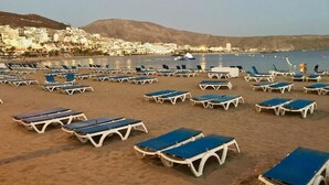 Una playa con filas de sillas y sombrillas azules y blancas.