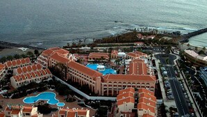 Un resort con varias construcciones, una piscina amplia y vista a la playa.