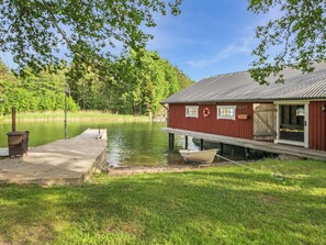 A dock extending into a calm lake with a red building adjacent to it. - Lilla nennebo by Interhome (Salo)