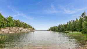 A calm lake with a sandy shore and a wooden dock extending into the water. - Lilla nennebo by Interhome (Salo)