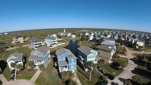 Ett bostadsområde vid kusten med flera tvåvåningshus, en liten sjö och en klar himmel.