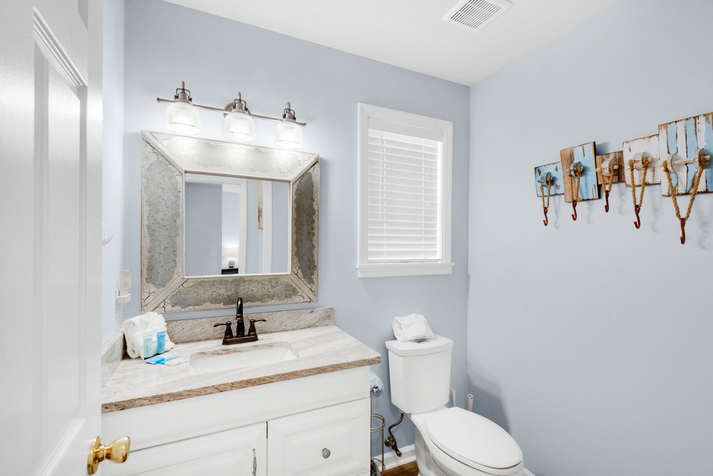 A bathroom with a marble sink, a white toilet, and a mirror with lights.