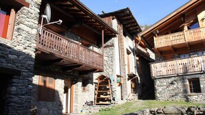 A traditional stone building with wooden balconies and a wooden staircase.