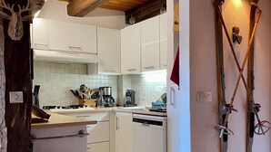 A kitchen with white cabinets, a wooden ceiling, and a built-in dishwasher.