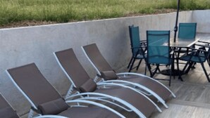 A row of lounge chairs and a table with chairs, likely part of a patio area.