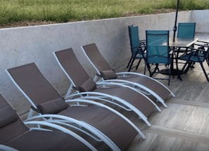 A row of lounge chairs and a table with chairs, likely part of a patio area.
