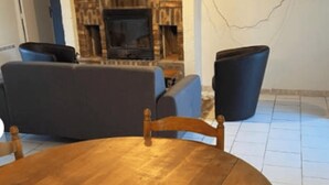 A room with a wooden table, two chairs, a sofa, and a fireplace.