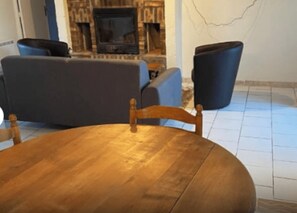 Una habitación con una mesa de comedor de madera, dos sofás y una chimenea.