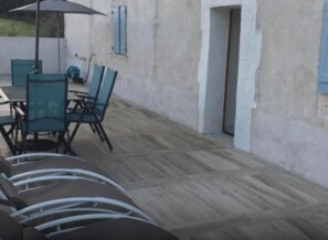 A patio with outdoor seating, including a table and chairs, and a covered area with an umbrella. - GITE COSMOS (Notre-Dame-de-Sanilhac)