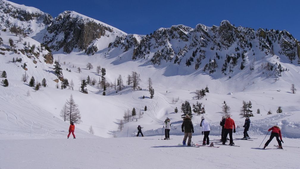 A snowy mountain slope with skiers.