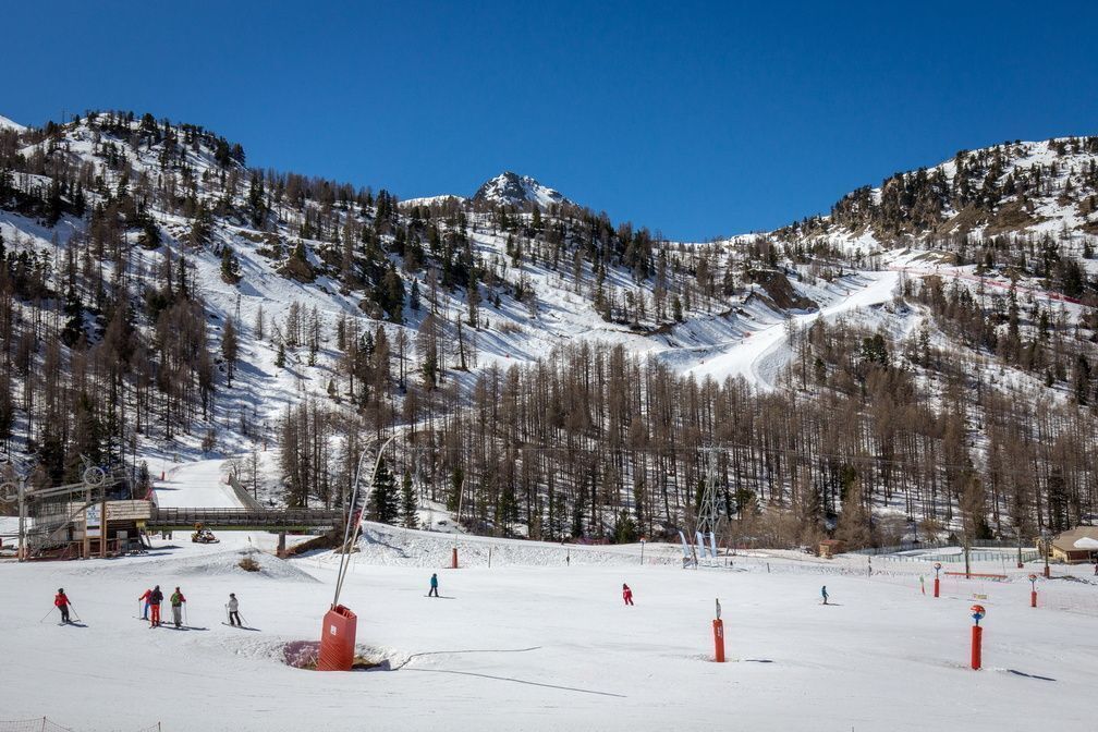 A ski resort with a chairlift, snow-covered slopes, and a mountain backdrop.
