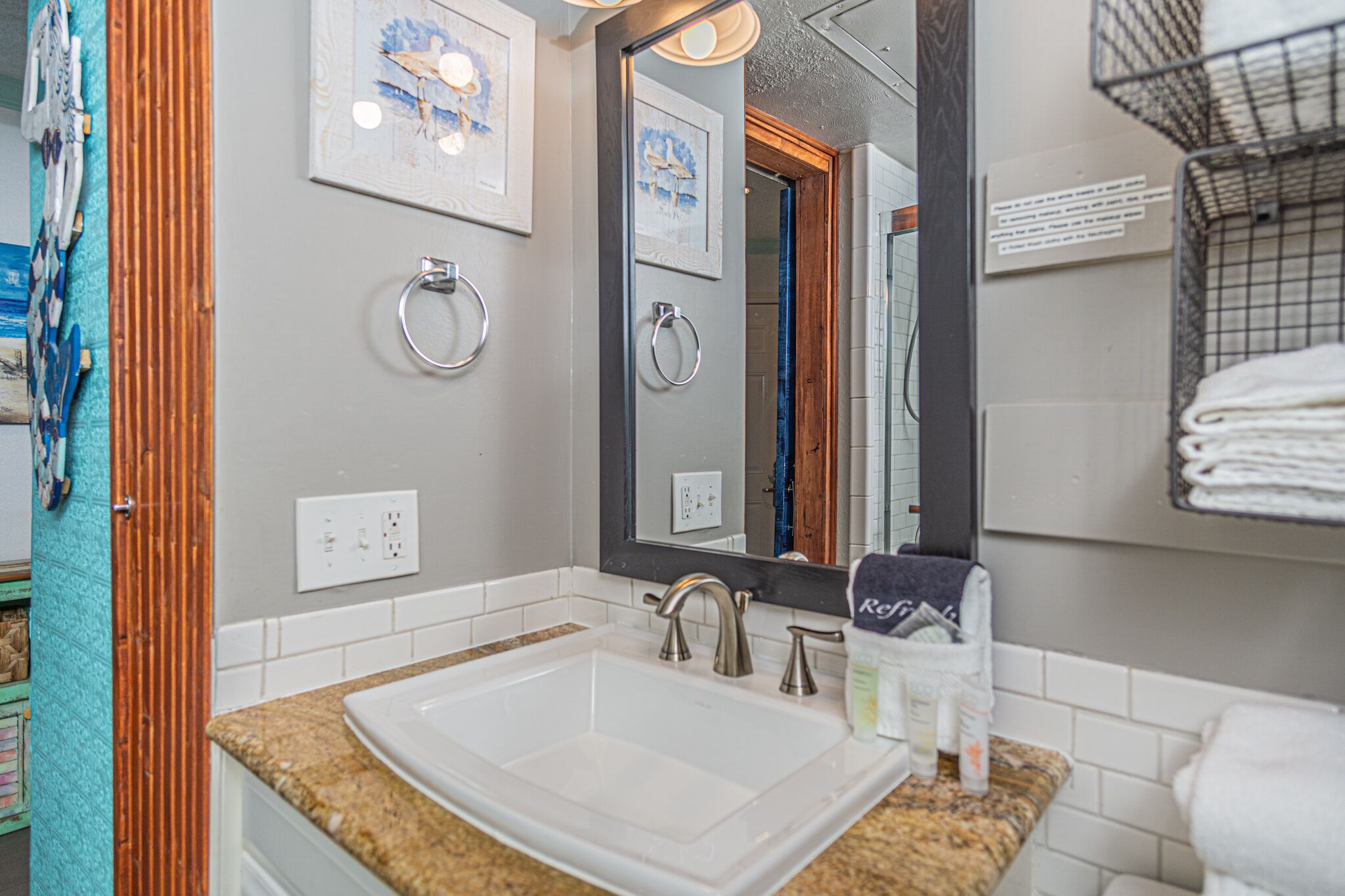 Une salle de bain avec un grand miroir, un lavabo et un porte-serviettes.