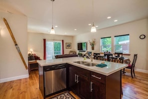 A modern kitchen with a dishwasher, a dining area with a table and chairs, and a large window.
