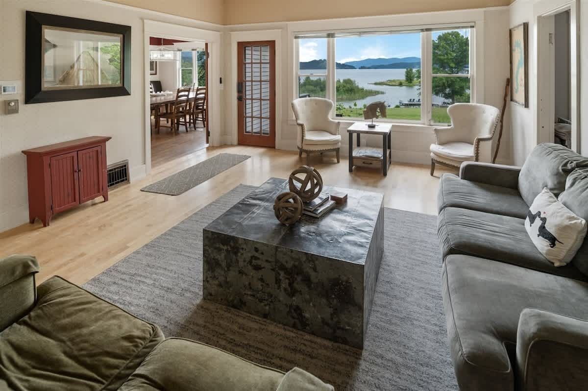 A spacious living room with a view of a lake, a dining area, and a cozy seating arrangement.