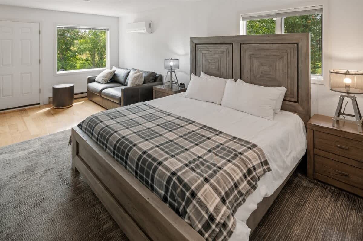Une chambre à coucher avec un grand lit, une table de chevet, une lampe, un canapé et une fenêtre donnant sur un paysage verdoyant.