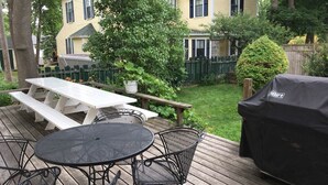 Una terrazza con un tavolo rotondo e sedie, un tavolo da picnic e un barbecue.