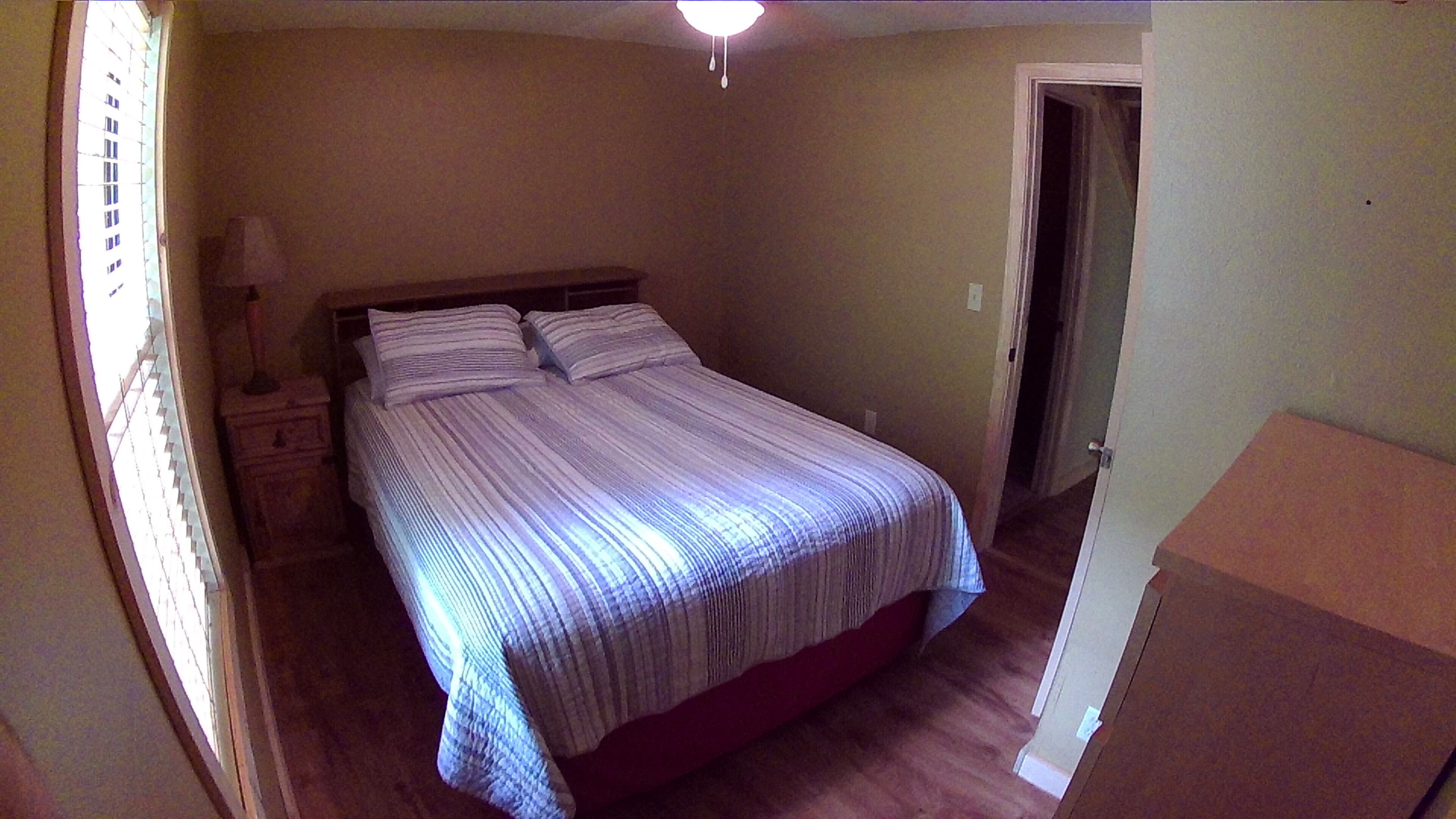 A bedroom with a bed, nightstands, a lamp, and a door.