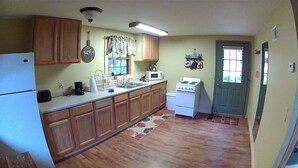 A compact kitchen with wooden cabinets, a refrigerator, a microwave, and a stove.