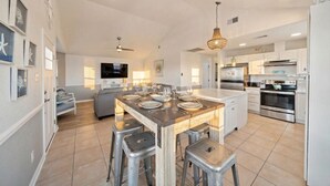 A spacious kitchen with a central island, bar stools, and modern appliances. - Beach Cottage with Soaking Pool & Outdoor Oasis (Galveston)