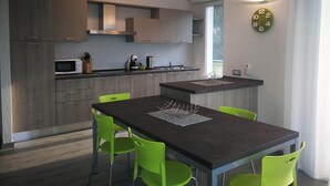 A modern kitchen with a dining area, featuring a microwave, kettle, and a clock on the wall. - Single house, 2 double and 1 single room A/C and wifi "La Svolta Holidays" (Malcesine)