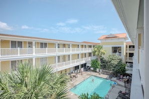 A multi-story hotel with a pool area, including a swimming pool and lounge chairs.