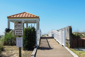 A private beach access path with a wooden walkway, white fence, and a gazebo. - Greyt Escape: Lovely, Ocean View Condo Across from OKI Pier with Community Pool, (Oak Island)