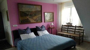 Un dormitorio con una cama grande, un banco de madera y dos cuadros en la pared.