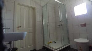 Un baño con ducha de vidrio, inodoro y lavabo.